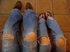 Four knees poking through holes in jeans