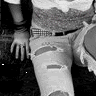 Black and white photo of a girl sitting down in ripped jeans